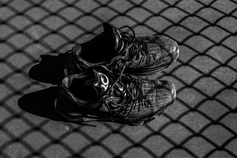 Black court shoes lying in the shadow of a pickleball net - Best pickleball shoes