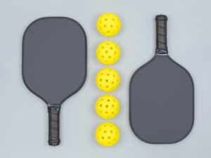 Two pickleball paddles separated by a line of yellow pickleballs - graphite vs fiberglass pickleball paddles